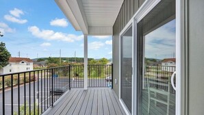 A balcony with a view of a parking lot and distant buildings.