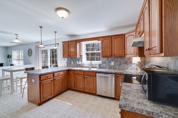 A modern kitchen with wooden cabinets, granite countertops, a dishwasher, and a built-in oven.