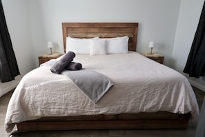 A large bed with a wooden headboard, white linens, and two bedside lamps.