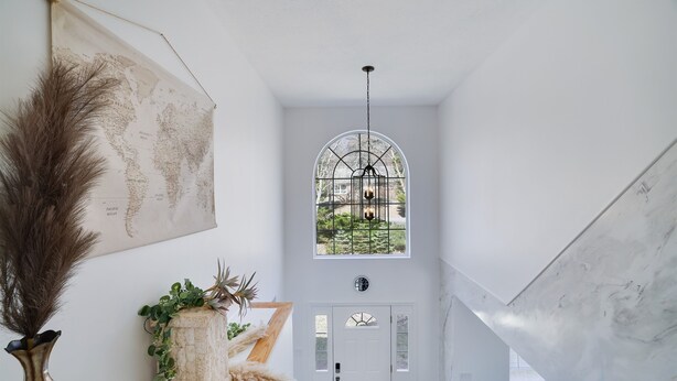 A hallway with a world map, a decorative vase, and a door with a window.