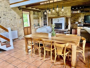 Un interior rústico con una mesa de comedor de madera, sillas, chimenea y televisor.