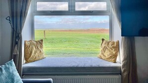 Een kamer met een groot raam, een blauwe muur en een aan de muur bevestigde televisie.