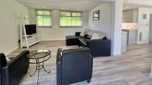 Una sala de estar moderna con un sofá, una mesa de centro y un televisor sobre un mueble blanco.