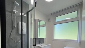 Un baño moderno con cabina de ducha de vidrio, un lavamanos blanco y un inodoro.
