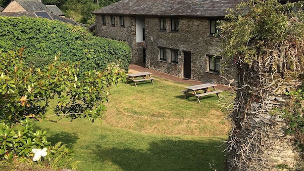 Ein Steinhaus mit einem Rasen und Picknicktischen.