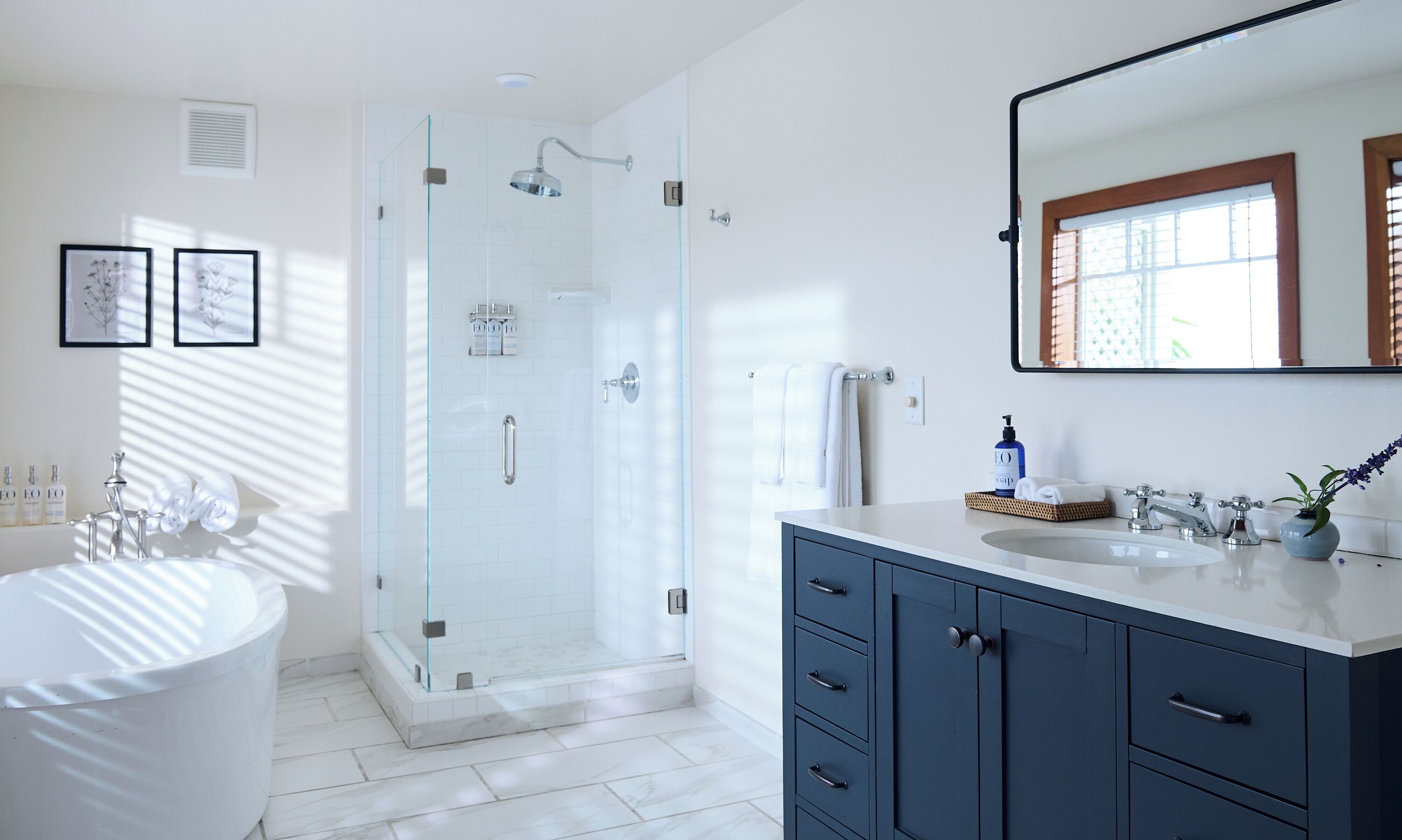 Une salle de bain moderne dotée d’une douche à parois de verre, d’une baignoire sur pieds et d’un meuble-lavabo avec un miroir.
