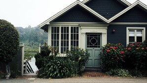 A house with a dark exterior, a green door, and a window with a circular glass design.