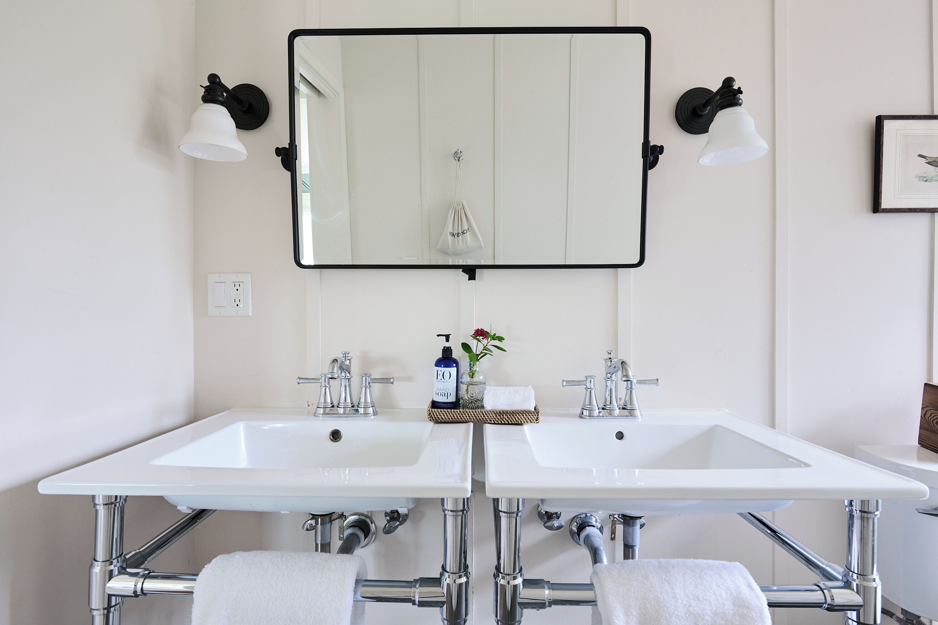 A bathroom with two white sinks, a large mirror, and two wall-mounted lights.