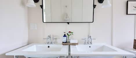 A bathroom with two white sinks, a large mirror, and two wall-mounted lights.