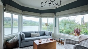 A cozy room with a blue sofa, a wooden coffee table, and a view of a lake.