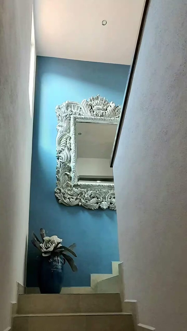 A staircase with a blue wall and a decorative mirror with an ornate frame.