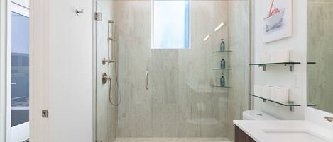 A modern bathroom with a glass-enclosed shower, a toilet, and a vanity with glass shelves.