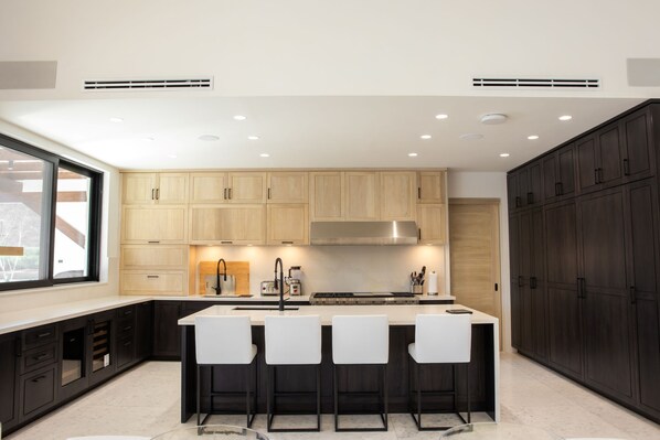 A modern kitchen with a central island, bar stools, and dark cabinetry.