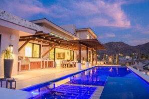 A modern outdoor pool area with a pergola, a bar, and a seating area.