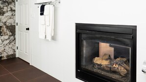 Una chimenea moderna con una pared de azulejos blancos y un piso de baldosas marrón oscuro.