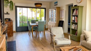 A spacious living room with a dining area, a bookshelf, and a view of the outdoors. - Beautiful  house in Loix (LOIX)