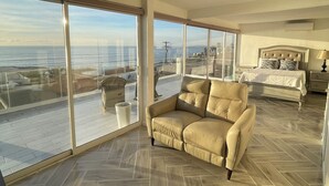 A spacious living room with large windows, a herringbone floor, and a view of the ocean. - Beautiful 4 story beach house with amazing rooftop located in  Tijuana-Rosarito. (Tijuana)