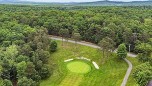 A golf course with a well-maintained putting green and a road running alongside it.