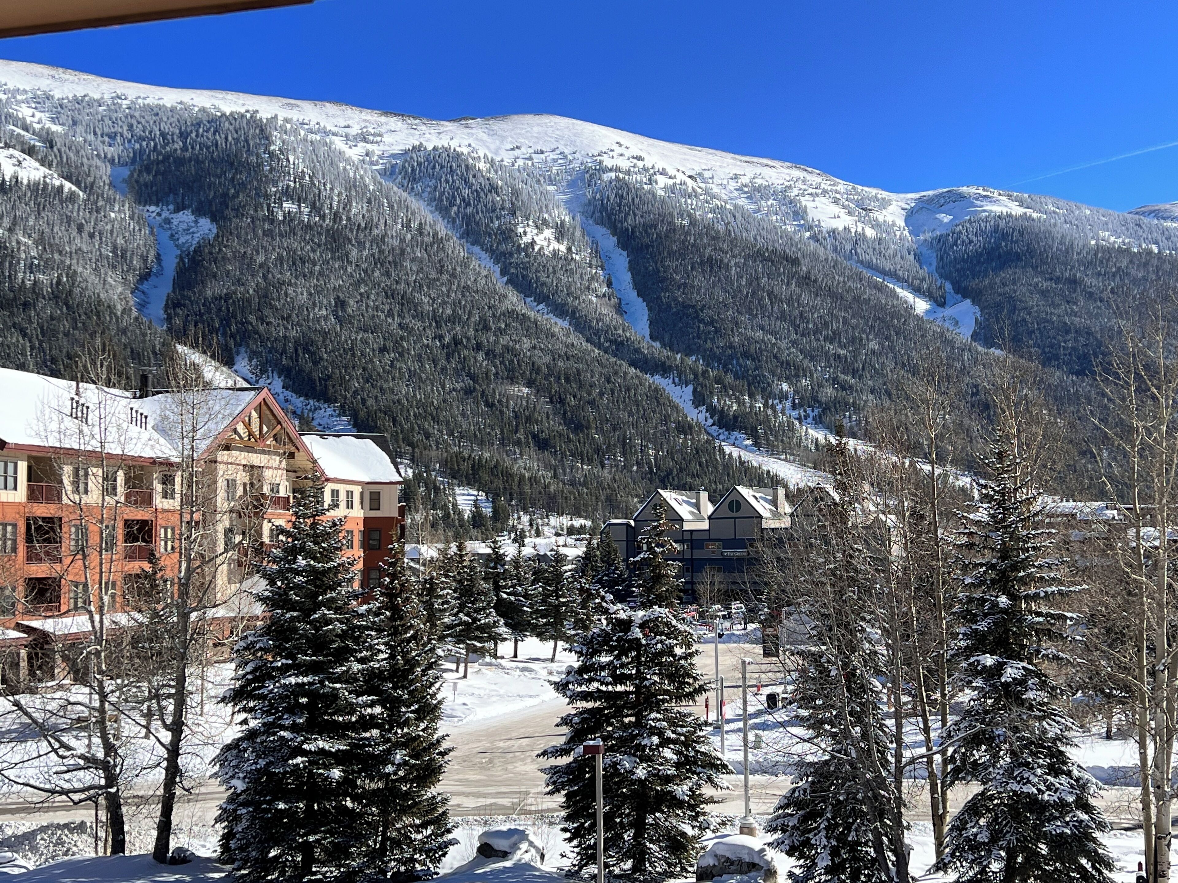 A snow-covered mountain landscape with a lodge featuring multiple buildings and a ski slope in the background.
