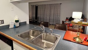 Een keuken met twee roestvrijstalen spoelbakken, een houten aanrechtblad en witte kasten.