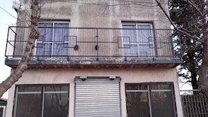 Un bâtiment à deux étages doté d’un balcon, de grandes fenêtres et d’une porte de garage.