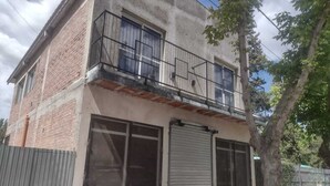 Un bâtiment à deux étages doté d’un balcon, de grandes fenêtres et d’une porte de garage.
