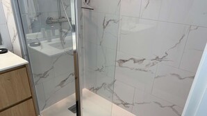 Ein modernes Badezimmer mit Duschkabine aus Glas, Marmorfliesen und einem Holzkabinent.