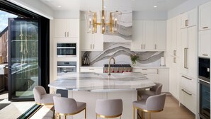 A modern kitchen with a central island, white cabinetry, and a marble backsplash.