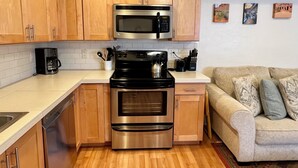 A modern kitchen with stainless steel appliances, wooden cabinets, and a white countertop.