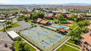 A residential area with a large tennis court, a swimming pool, and surrounding houses.
