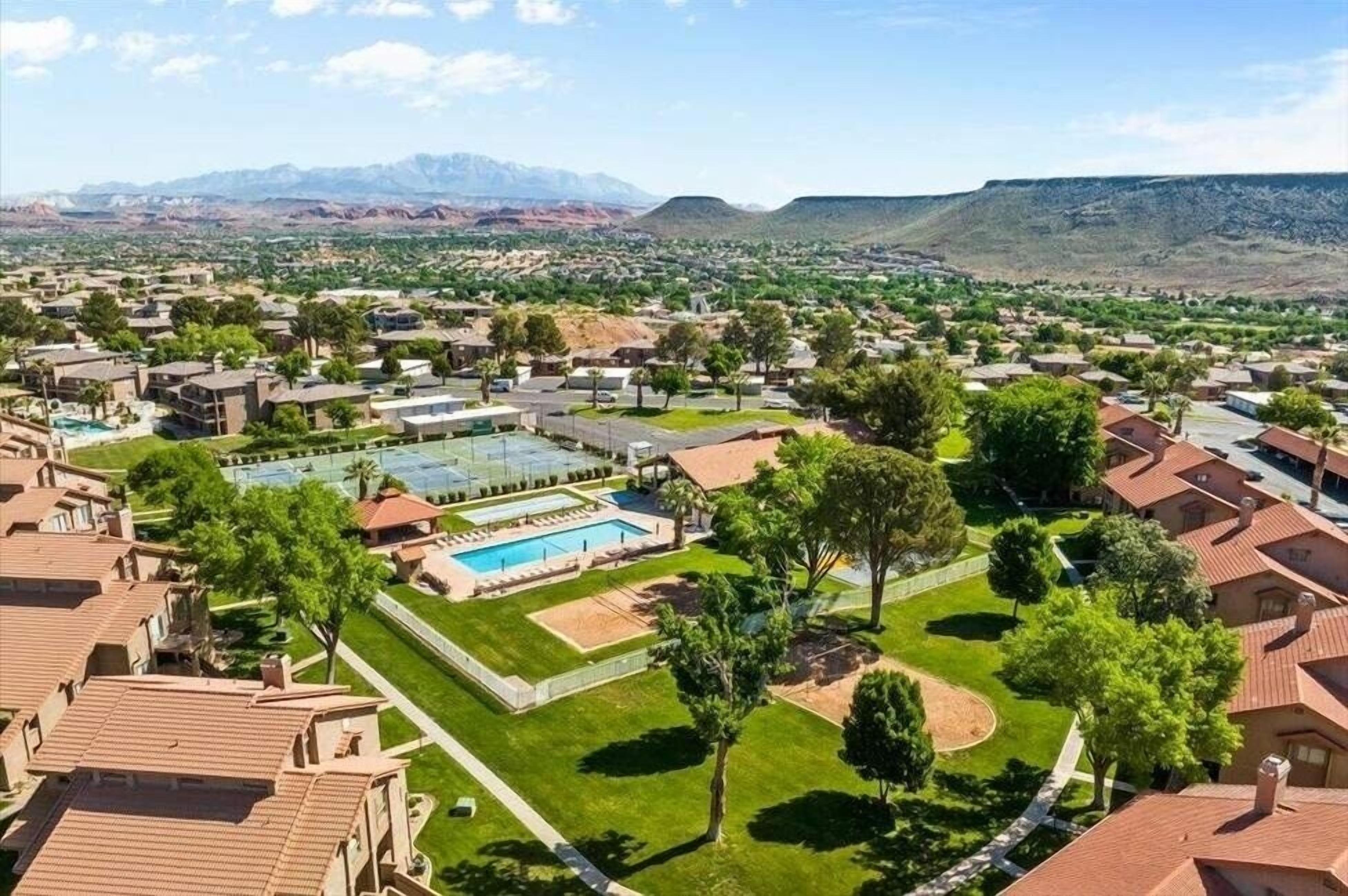 Un quartier résidentiel comprenant plusieurs immeubles, une piscine et un paysage montagneux en arrière-plan.