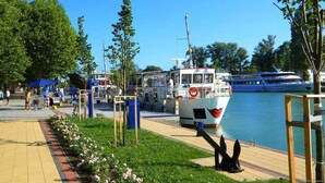 Ein Uferbereich mit Anlegesteg, einem Boot und einem Fußweg.