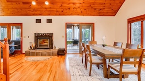 Un interior acogedor con chimenea, piso de madera y una zona de comedor con sillas y una mesa.