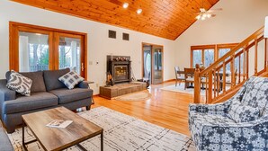 Amplia sala de estar con chimenea, piso de madera y una escalera que lleva a un balcón.