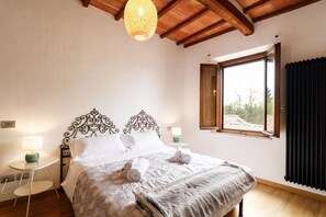 A bedroom with a bed, a bedside table, a lamp, a window with curtains, and a ceiling light.