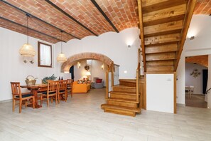 A spacious living area with a wooden staircase, a dining set, and a cozy seating area.