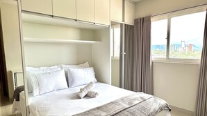 Un dormitorio moderno con una cama grande, armario empotrado y vistas a la ciudad desde la ventana.