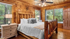 A wooden cabin bedroom with a bed, nightstands, and a ceiling fan. - Romantic Retreat!!! Newly refreshed cabin with hot tub~New listing rates! (Sevierville)