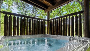 A hot tub with a wooden deck and a view of trees. - Romantic Retreat!!! Newly refreshed cabin with hot tub~New listing rates! (Sevierville)