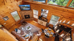 A cozy cabin interior with a fireplace, wooden walls, a dining area, and a living room with a sofa and coffee table. - Romantic Retreat!!! Newly refreshed cabin with hot tub~New listing rates! (Sevierville)