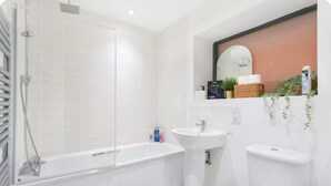 A modern bathroom with a bathtub, a pedestal sink, and a toilet.