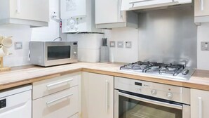 A modern kitchen with white cabinets, a microwave, a gas stove, and an oven.