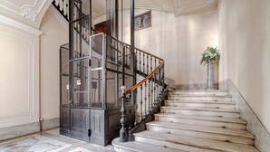 Una imponente escalera con barandilla de metal negro y escalones de mármol, que conduce a un piso superior.