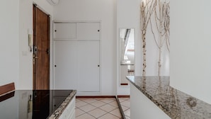 Un pasillo con una puerta blanca, una puerta de madera, una encimera de mármol y un suelo de baldosas.