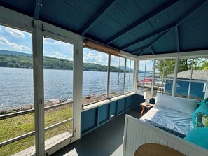A room with a bed, a small table, and a window overlooking a lake. - Rustic 4-bedroom cabin with WiFi, AC in charming Alton Bay on Lake Winni. (Alton)