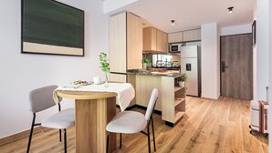 A modern kitchen with wooden cabinets, a central island, and a dining area with two chairs and a table. - Hestia at Thames 2200 (Buenos Aires)
