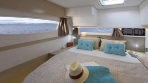 Een slaapkamer met een bed, een raam met uitzicht op zee, een dakraam en een nachtkastje.