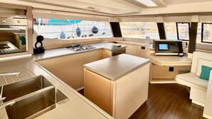 Een moderne keuken met roestvrijstalen apparatuur, een centraal eiland en een zithoek met een beklede bank.
