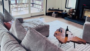 A modern living room with a grey sofa, a wooden coffee table, and a fireplace. - Dual Peaks Gem $1M Sharp Views /HOT TUB & WiFi (Tuckasegee)