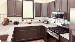 A kitchen with dark cabinets, a microwave, a stove, and a window with blinds. - Dual Peaks Gem $1M Sharp Views /HOT TUB & WiFi (Tuckasegee)